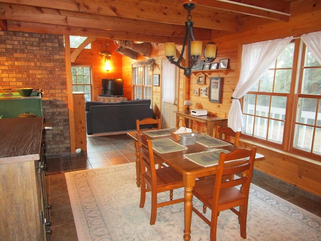 tiled dining area with an inviting chandelier, wooden walls, and brick wall