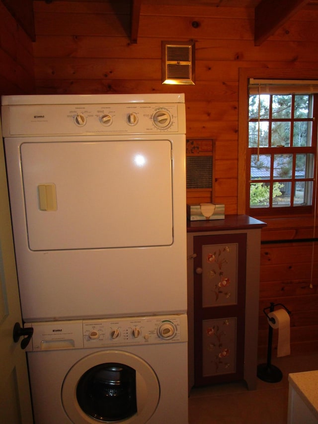 laundry room with wooden walls and stacked washer and dryer