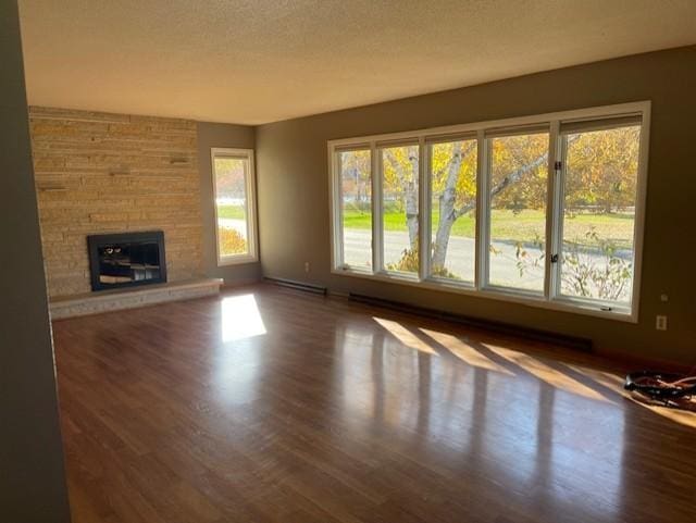 unfurnished living room featuring dark hardwood / wood-style floors, a baseboard radiator, a textured ceiling, and a fireplace