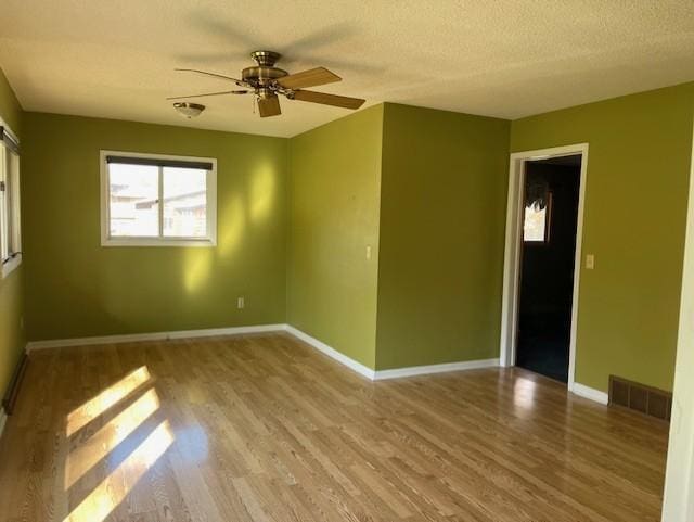 spare room featuring a textured ceiling, light hardwood / wood-style floors, and ceiling fan