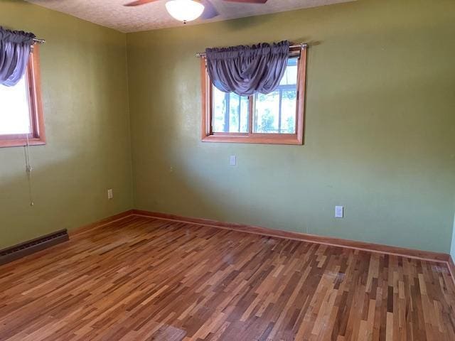 unfurnished room featuring ceiling fan, hardwood / wood-style flooring, and plenty of natural light