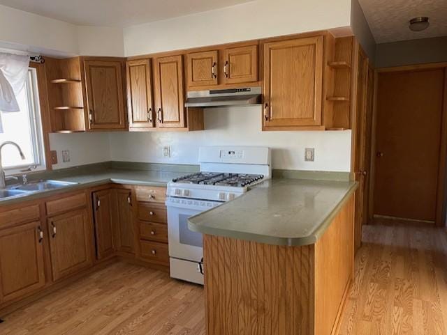 kitchen with kitchen peninsula, white gas stove, sink, and light wood-type flooring