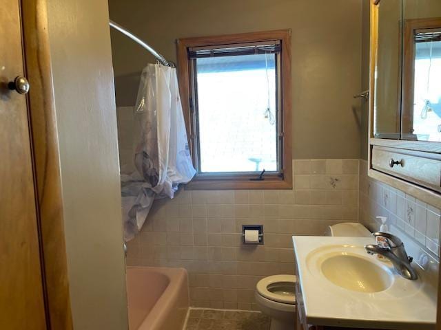 full bathroom featuring a wealth of natural light, vanity, toilet, and tile walls