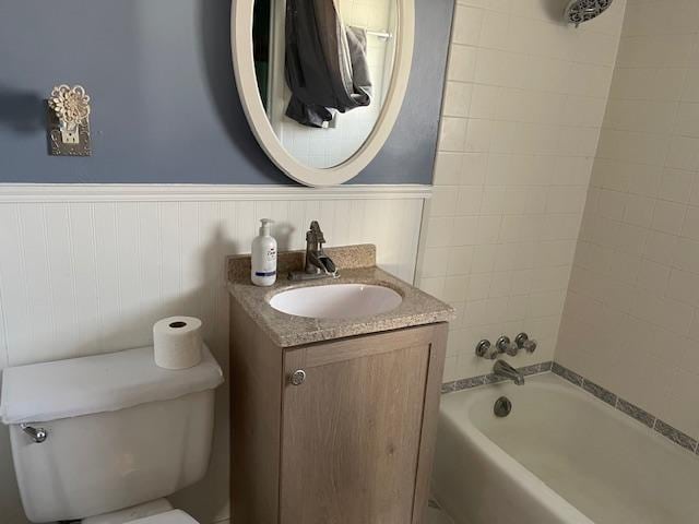 full bathroom featuring tiled shower / bath, vanity, and toilet