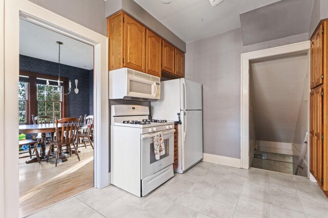 kitchen featuring light wood-type flooring, a notable chandelier, and white appliances