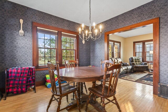 dining room with a wealth of natural light, wood-type flooring, and a notable chandelier