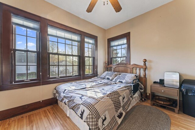 bedroom featuring ceiling fan, multiple windows, and light wood-type flooring