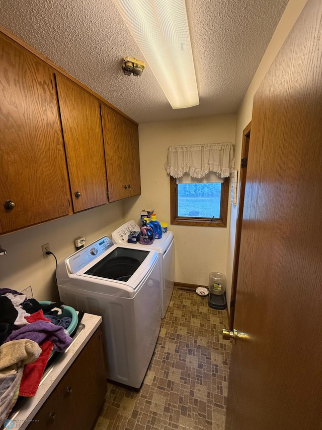 laundry room with a textured ceiling, cabinets, and separate washer and dryer