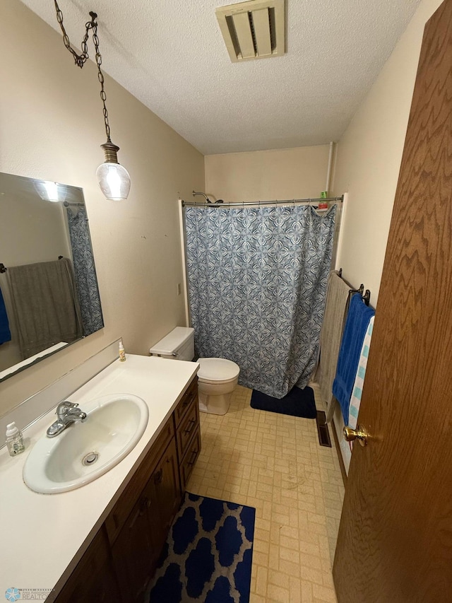 bathroom featuring vanity, toilet, a textured ceiling, and a shower with curtain