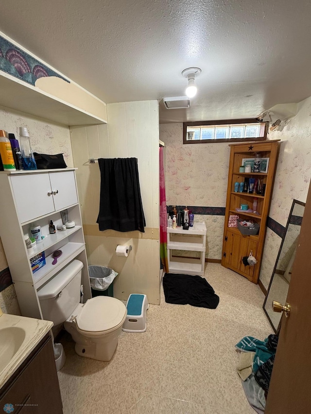 bathroom featuring vanity, toilet, a textured ceiling, and curtained shower