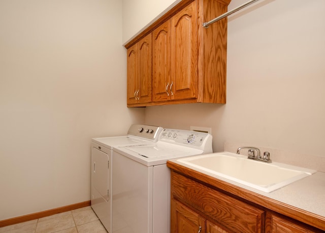 clothes washing area with sink, washer and clothes dryer, light tile patterned floors, and cabinets