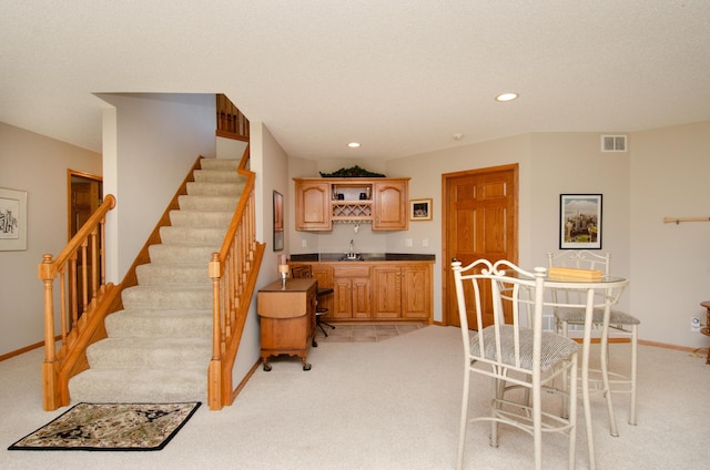 carpeted dining area featuring wet bar and a textured ceiling