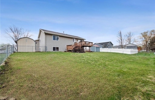 back of house with a deck, a yard, an outbuilding, and a fenced backyard