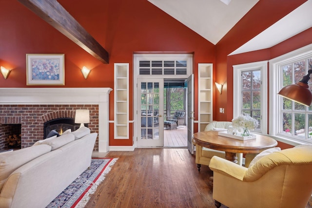 living room with hardwood / wood-style floors, lofted ceiling with beams, and a brick fireplace