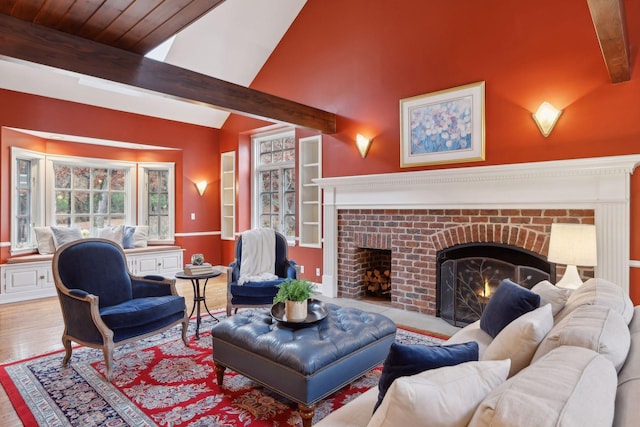 living room with a brick fireplace, lofted ceiling with beams, and light wood-type flooring