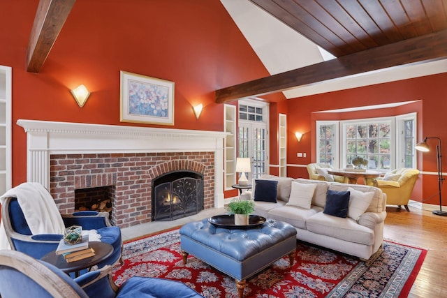 living room with a brick fireplace, light hardwood / wood-style flooring, and vaulted ceiling with beams