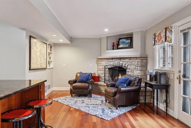 living room featuring ornamental molding, light wood-type flooring, and a fireplace