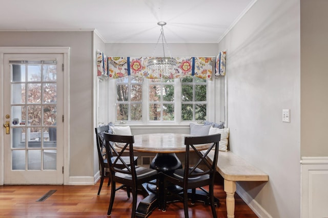 dining area featuring hardwood / wood-style flooring, ornamental molding, and a notable chandelier