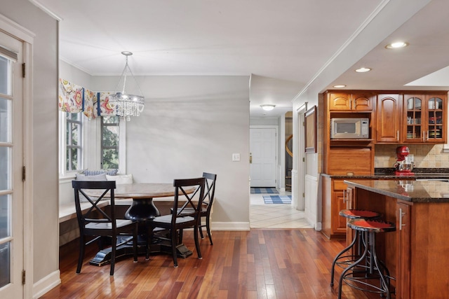 dining space with hardwood / wood-style flooring, crown molding, and a notable chandelier