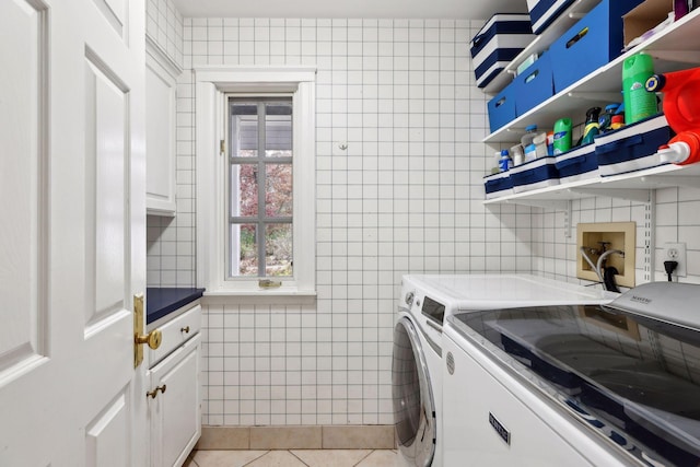 laundry area featuring cabinets, separate washer and dryer, light tile patterned floors, and tile walls