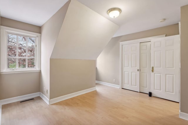 additional living space with light hardwood / wood-style flooring and vaulted ceiling