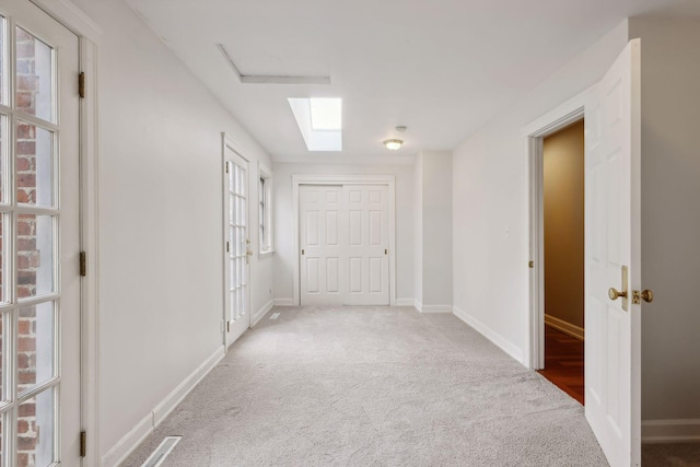 corridor with a skylight, a healthy amount of sunlight, and carpet floors