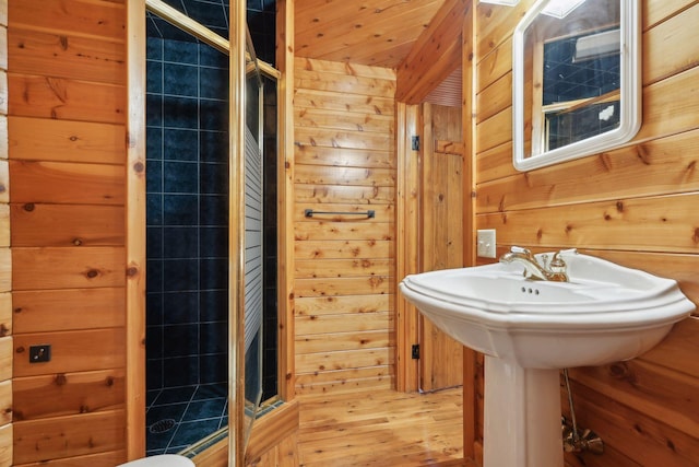 bathroom with wooden walls, hardwood / wood-style floors, and a tile shower