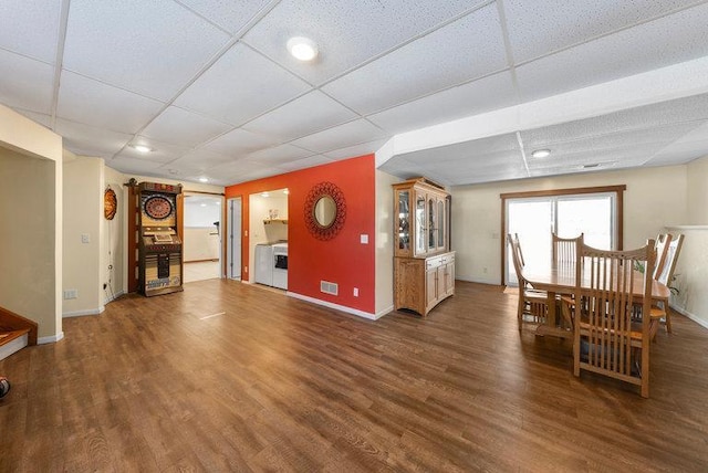 living room with dark hardwood / wood-style floors, a paneled ceiling, and washer / clothes dryer