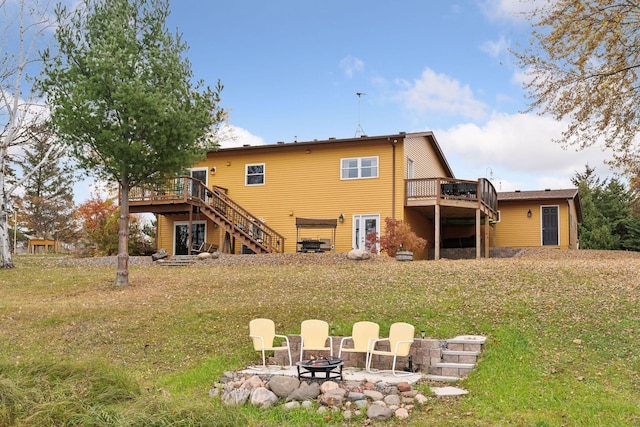 rear view of house featuring a lawn, an outdoor fire pit, and a wooden deck