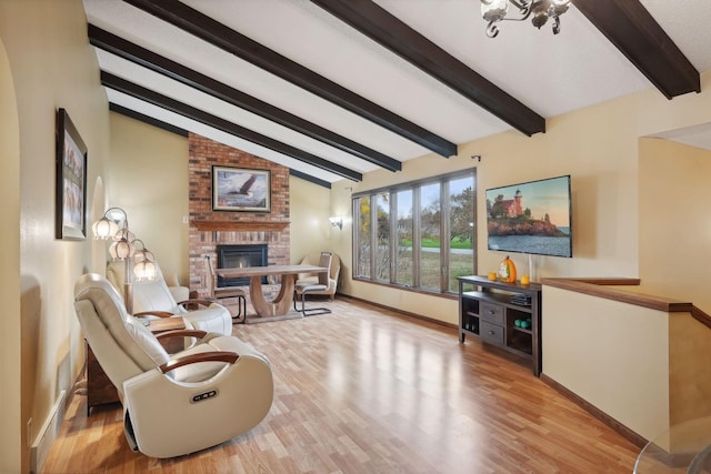 living room with a fireplace, light hardwood / wood-style flooring, a chandelier, and vaulted ceiling with beams