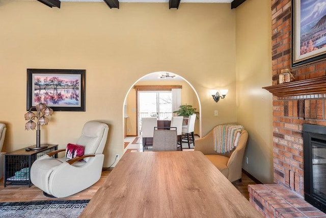 interior space featuring beamed ceiling, a brick fireplace, and wood-type flooring