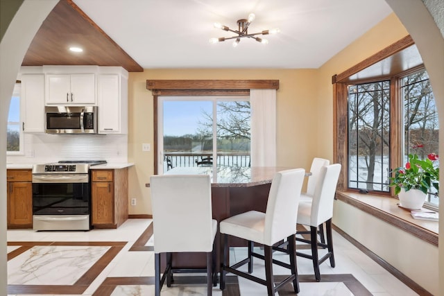 dining space with a water view, an inviting chandelier, and light tile patterned flooring