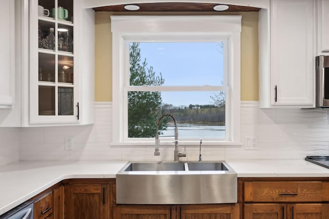 kitchen featuring sink, white cabinetry, stainless steel dishwasher, and tasteful backsplash