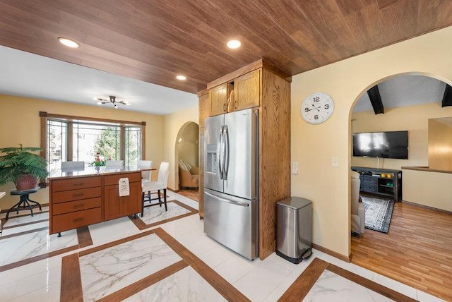 kitchen featuring a breakfast bar area, stainless steel fridge with ice dispenser, and wood ceiling