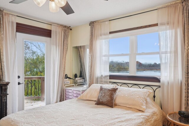 bedroom with ceiling fan, access to exterior, multiple windows, and a water view