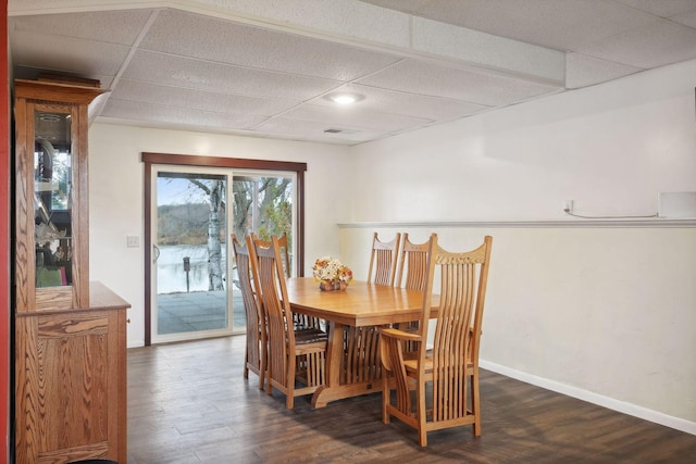 dining area with a paneled ceiling and dark hardwood / wood-style floors