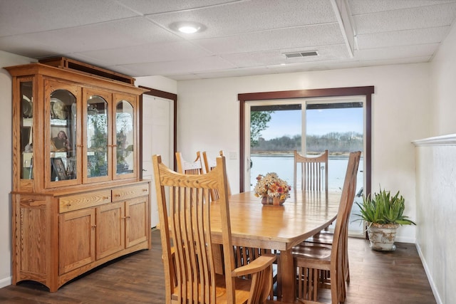 dining space with a water view and dark hardwood / wood-style floors