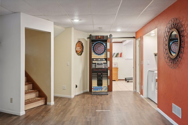 interior space with wood-type flooring, a drop ceiling, and washer / dryer