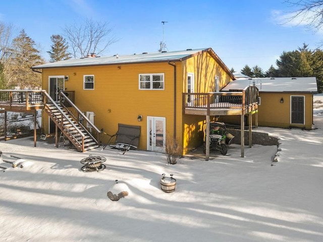 snow covered back of property featuring an outdoor fire pit and a wooden deck