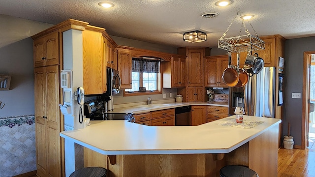 kitchen featuring appliances with stainless steel finishes, kitchen peninsula, a textured ceiling, and a kitchen bar