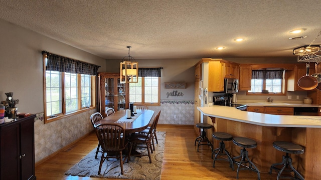 dining area featuring light wood-type flooring, a textured ceiling, and plenty of natural light