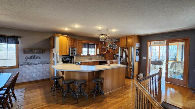 kitchen featuring kitchen peninsula, a kitchen breakfast bar, light wood-type flooring, black appliances, and sink