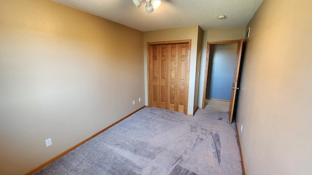 unfurnished bedroom featuring a textured ceiling, a closet, and light colored carpet