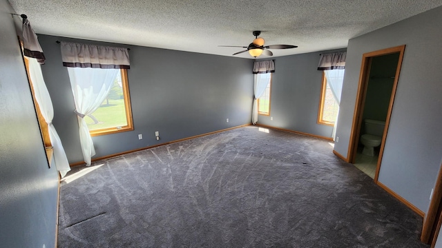 unfurnished room featuring a wealth of natural light, dark carpet, and ceiling fan