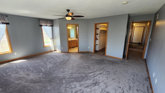 unfurnished bedroom featuring light carpet, ceiling fan, a spacious closet, a closet, and ensuite bath