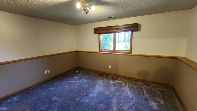 carpeted empty room with a textured ceiling