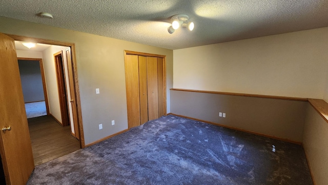 unfurnished bedroom with a closet, a textured ceiling, and dark colored carpet