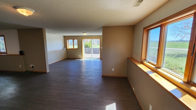 empty room with a textured ceiling and dark hardwood / wood-style flooring