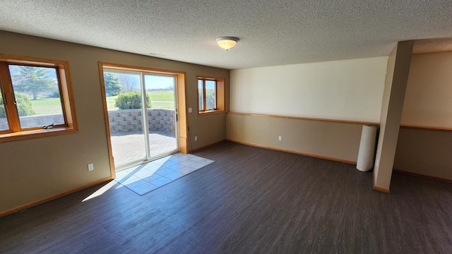 spare room with a textured ceiling and dark hardwood / wood-style floors