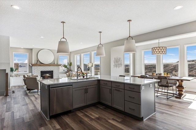 kitchen featuring pendant lighting, a center island with sink, stainless steel dishwasher, and sink